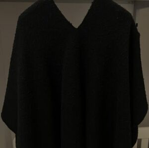 Poncho cape with central opening for the head and wider opening on one shoulder.